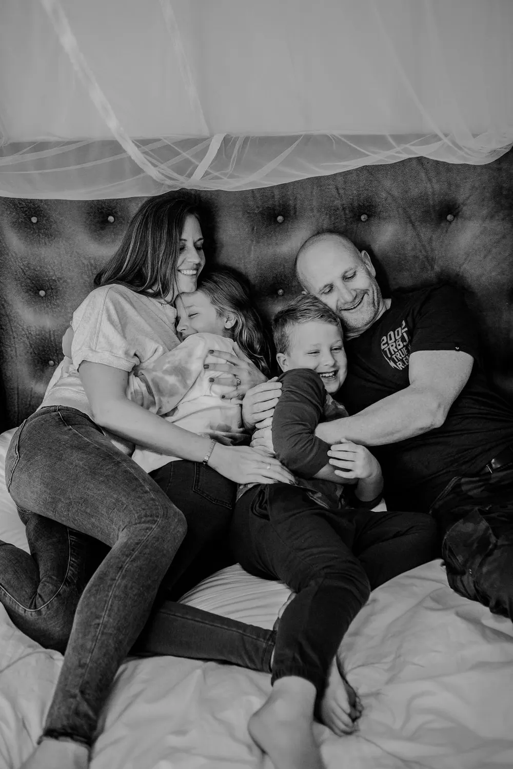 A family laughing and cuddling together on a bed