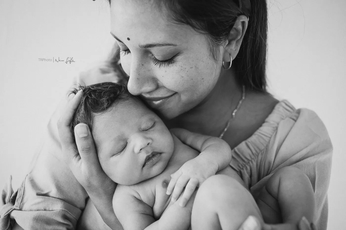 A mother cuddling her sleeping newborn